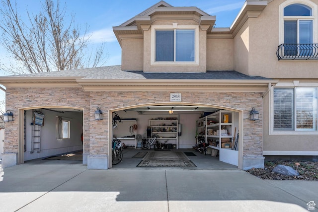 back of property featuring driveway, stucco siding, and stone siding