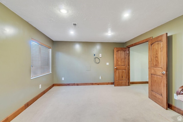 unfurnished room with a textured ceiling, light colored carpet, visible vents, recessed lighting, and baseboards