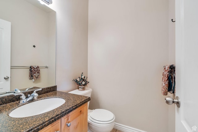 bathroom with toilet, vanity, and baseboards