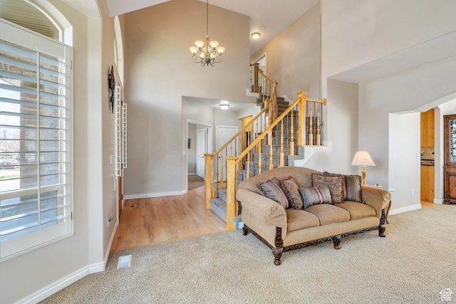 living area with a towering ceiling, baseboards, a chandelier, stairway, and carpet