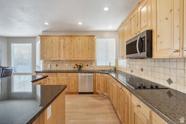kitchen with light wood-type flooring, appliances with stainless steel finishes, a sink, and light brown cabinets