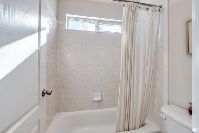 bathroom featuring toilet and shower / bath combination with curtain