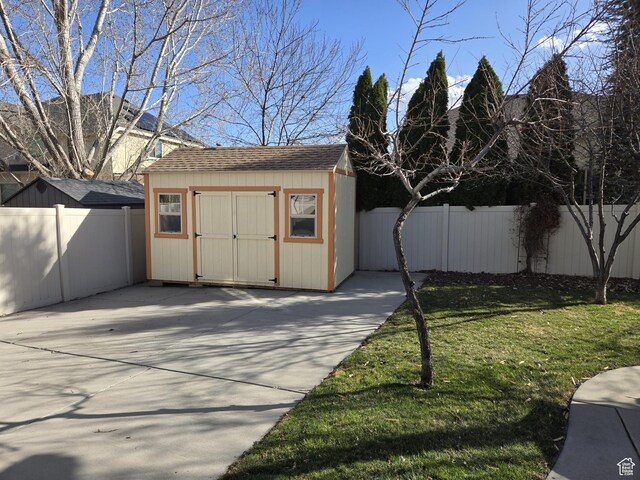 view of shed with a fenced backyard and concrete driveway