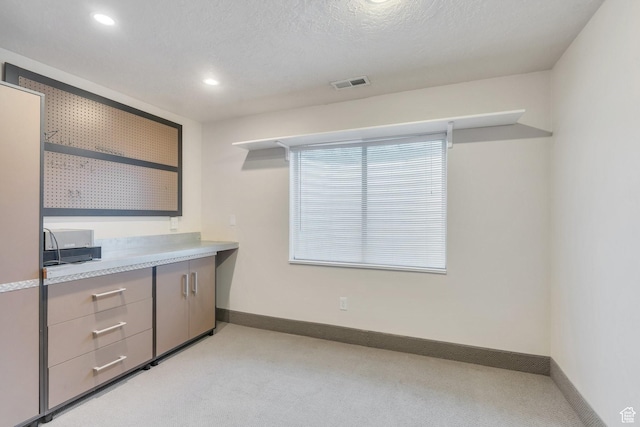 interior space featuring baseboards, light carpet, gray cabinetry, and visible vents