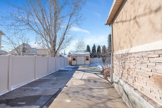view of side of property with a shed, a fenced backyard, stucco siding, and an outdoor structure