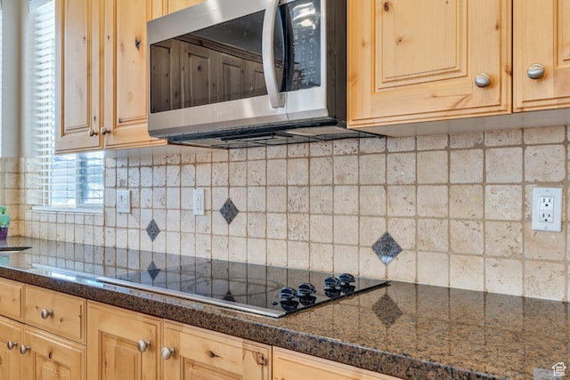 kitchen with stainless steel microwave, black electric stovetop, light brown cabinetry, and decorative backsplash