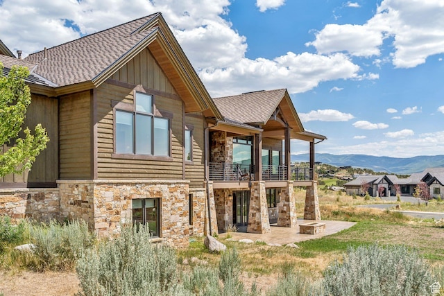 1075 N Oquirrh Mountain Dr Unit 64, Heber City, UT 84032 - back of house with stone siding, a balcony, a patio area, a mountain view, and roof with shingles