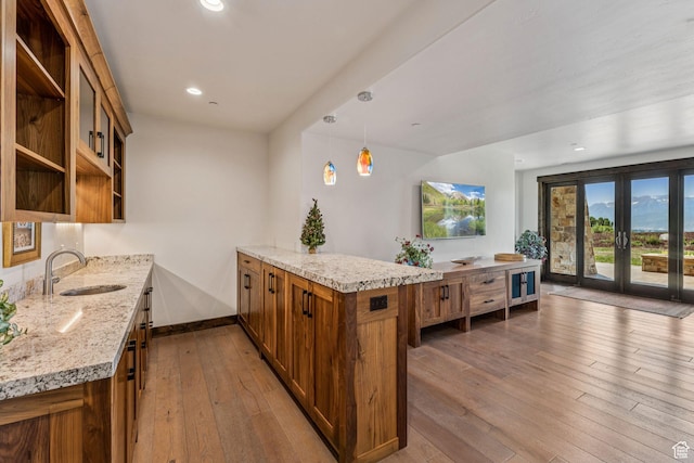 1075 N Oquirrh Mountain Dr Unit 64, Heber City, UT 84032 - kitchen featuring a peninsula, brown cabinetry, open shelves, light stone countertops, and hardwood / wood-style flooring