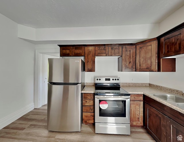 672 N 200 W, Salt Lake City, UT 84103 - kitchen with light wood finished floors, a sink, baseboards, light countertops, and appliances with stainless steel finishes