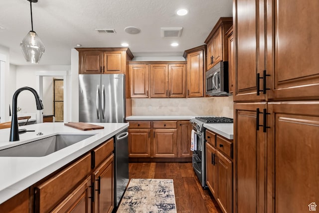 kitchen featuring brown cabinetry, visible vents, appliances with stainless steel finishes, and a sink