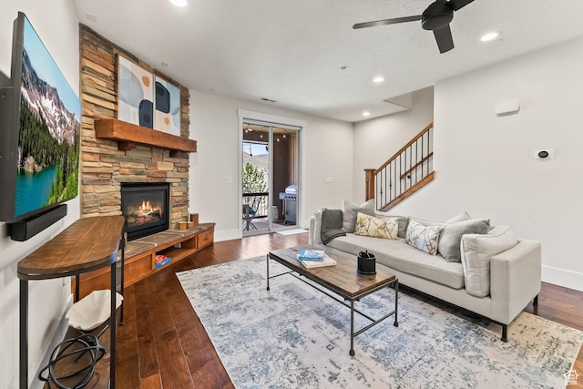 living room with baseboards, hardwood / wood-style floors, a stone fireplace, recessed lighting, and a ceiling fan