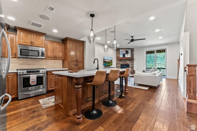 kitchen featuring ceiling fan, open floor plan, light countertops, brown cabinetry, and stainless steel appliances