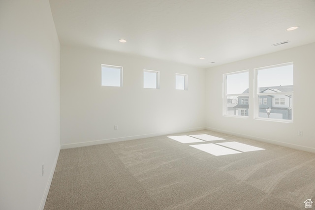 empty room featuring baseboards, light carpet, and recessed lighting