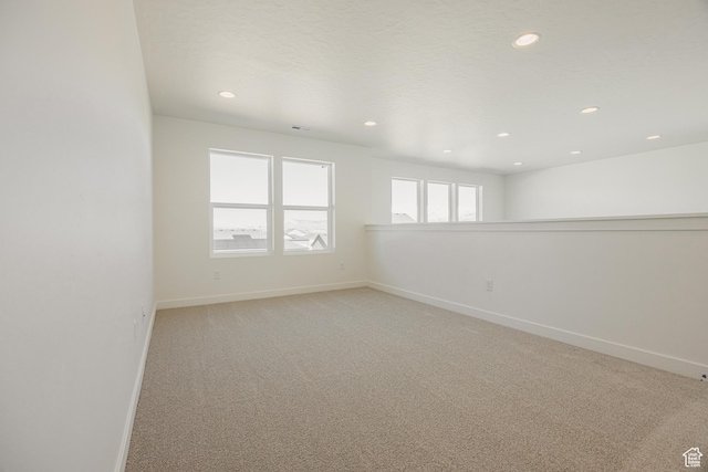 empty room featuring baseboards, light colored carpet, and recessed lighting