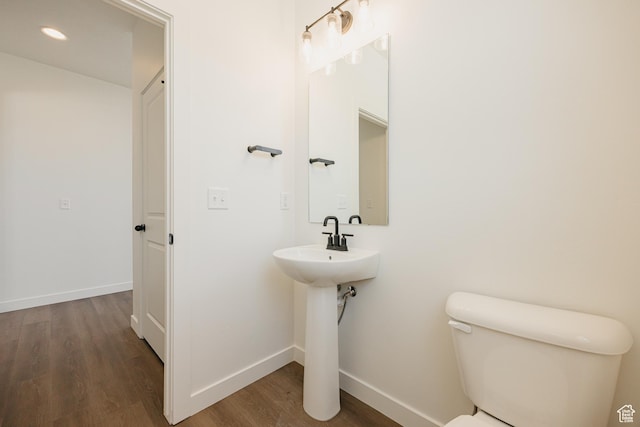 half bathroom with wood finished floors, baseboards, toilet, and recessed lighting