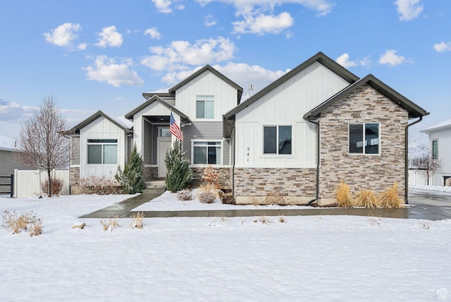 modern farmhouse style home featuring stone siding, board and batten siding, and fence