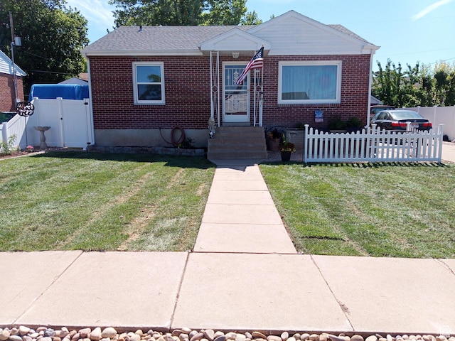 bungalow-style home featuring brick siding, fence private yard, a gate, and a front lawn