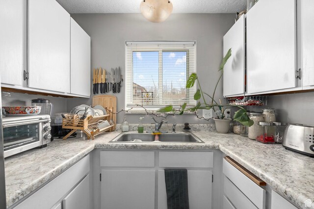 2670 S Melville Dr, Magna, UT 84044 - kitchen with white cabinetry, light countertops, a textured ceiling, and a sink