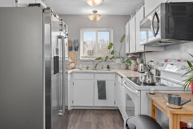 2670 S Melville Dr, Magna, UT 84044 - kitchen with a sink, a textured ceiling, wood finished floors, appliances with stainless steel finishes, and light countertops