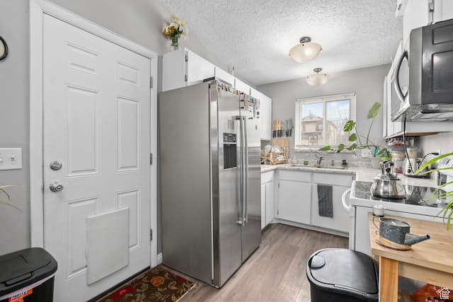 2670 S Melville Dr, Magna, UT 84044 - kitchen featuring a textured ceiling, appliances with stainless steel finishes, white cabinetry, and light wood-style floors