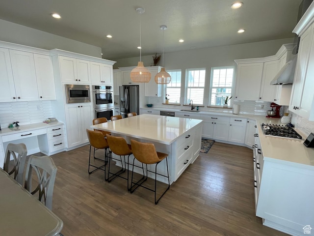 10887 S Lamond Dr, South Jordan, UT 84009 - kitchen featuring range hood, a kitchen island, a breakfast bar, stainless steel appliances, and white cabinets