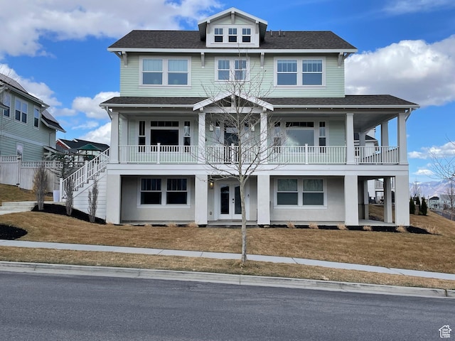 view of front facade featuring a balcony, french doors, and roof with shingles