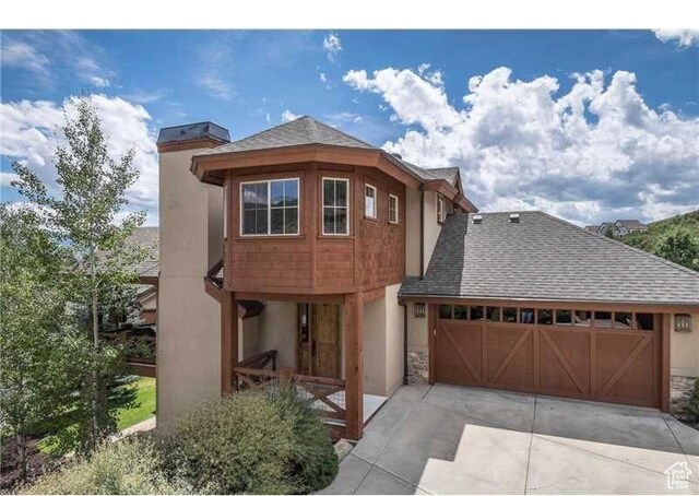 view of front of property featuring stucco siding, concrete driveway, a garage, and a shingled roof