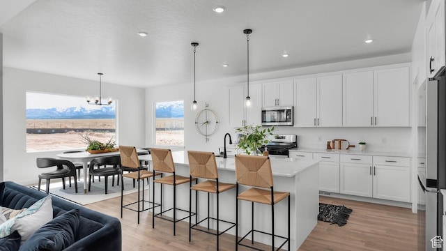 kitchen with light wood finished floors, open floor plan, light countertops, appliances with stainless steel finishes, and a chandelier