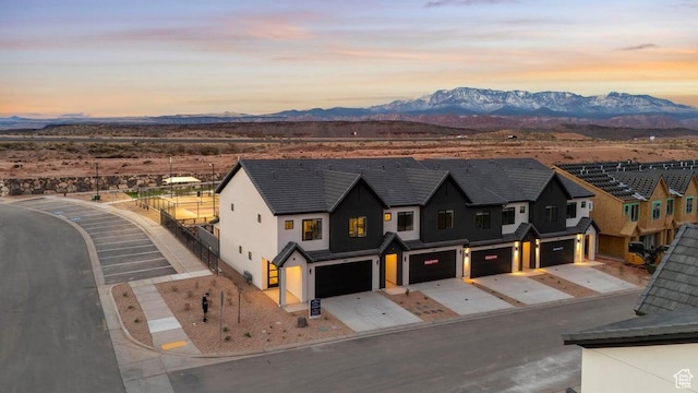 view of front facade with a residential view, stucco siding, concrete driveway, a garage, and a mountain view