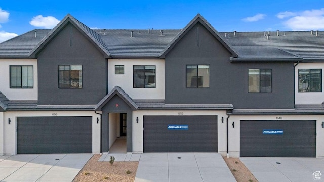multi unit property featuring concrete driveway, an attached garage, and stucco siding