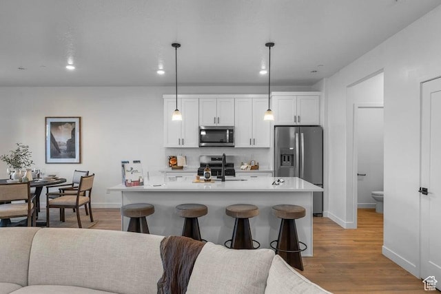 kitchen with decorative backsplash, light countertops, white cabinets, appliances with stainless steel finishes, and light wood-type flooring