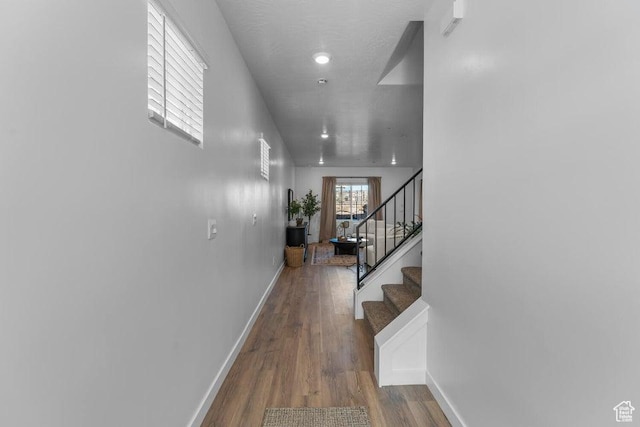 hall featuring stairway, baseboards, and wood finished floors