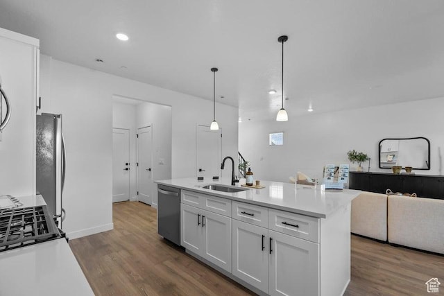 kitchen with wood finished floors, appliances with stainless steel finishes, white cabinetry, and a sink