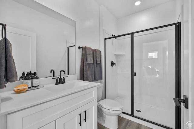 bathroom featuring a stall shower, toilet, vanity, and wood finished floors