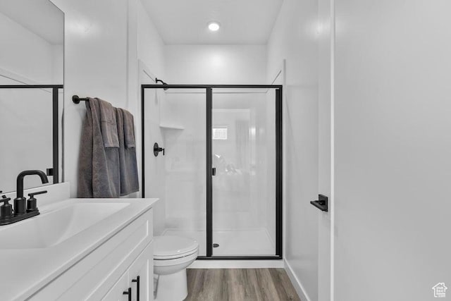 full bath with a stall shower, toilet, vanity, and wood finished floors