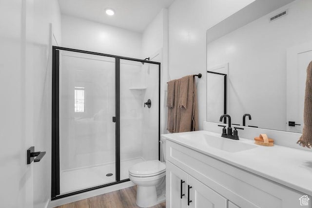 bathroom featuring visible vents, toilet, wood finished floors, and a stall shower