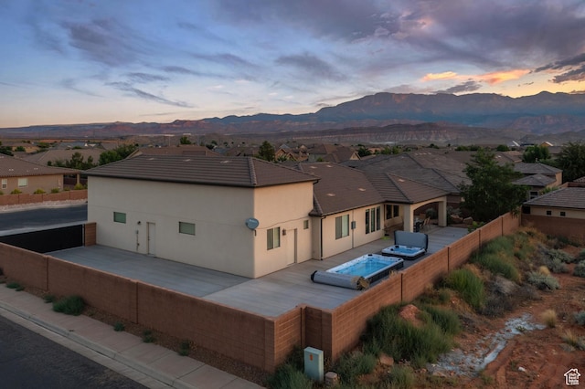 2691 S 3970 W, Hurricane, UT 84737 - back of house at dusk with a mountain view, fence, hot tub deck surround, and stucco siding
