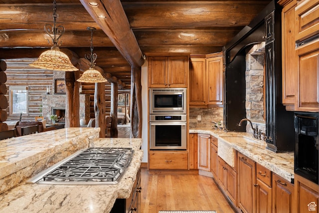 4115 Moose Hollow Loop, Park City, UT 84098 - kitchen with stainless steel appliances, rustic walls, light wood finished floors, a sink, and light stone countertops