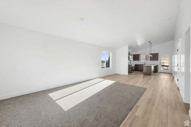1667 S Marigold Way Unit 230E, Santaquin, UT 84655 - unfurnished living room featuring a sink, high vaulted ceiling, baseboards, and light wood finished floors