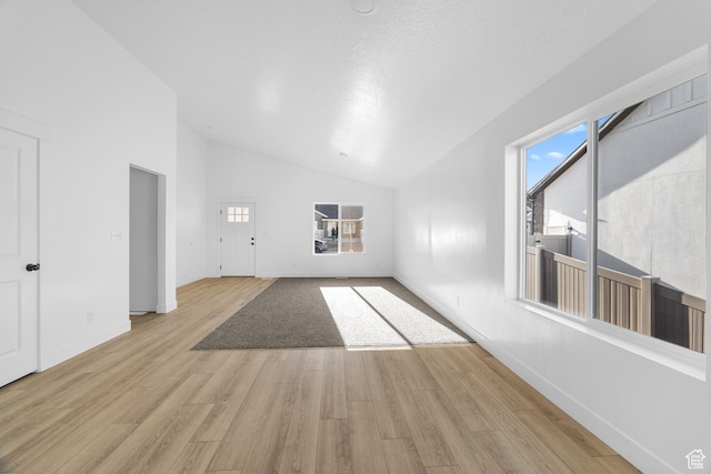 1667 S Marigold Way Unit 230E, Santaquin, UT 84655 - unfurnished living room with light wood-style flooring, high vaulted ceiling, baseboards, and a textured ceiling