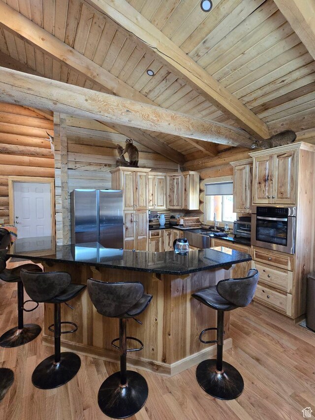 365 W Sleeping Rainbow Dr, Torrey, UT 84775 - kitchen featuring beamed ceiling, log walls, a kitchen bar, appliances with stainless steel finishes, and light wood-style floors