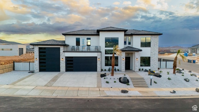 view of front of house with a gate, fence, driveway, stucco siding, and stone siding