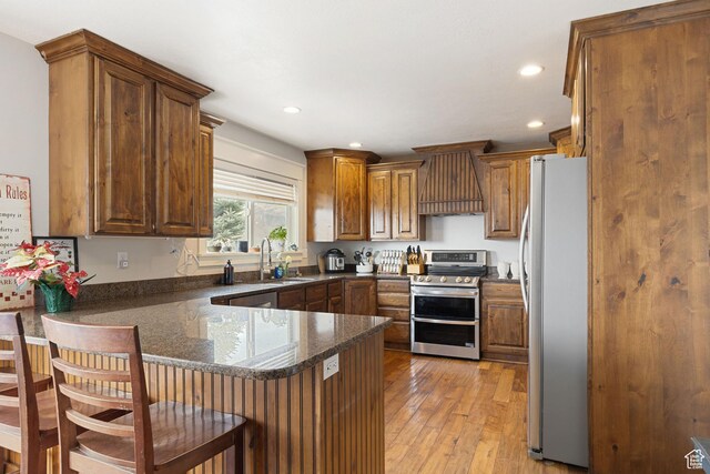 1035 E 300 S, Santaquin, UT 84655 - kitchen with custom range hood, stainless steel appliances, a sink, light wood-style flooring, and a peninsula