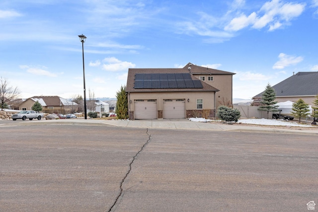 1035 E 300 S, Santaquin, UT 84655 - view of front of house with stone siding, driveway, roof mounted solar panels, an attached garage, and stucco siding