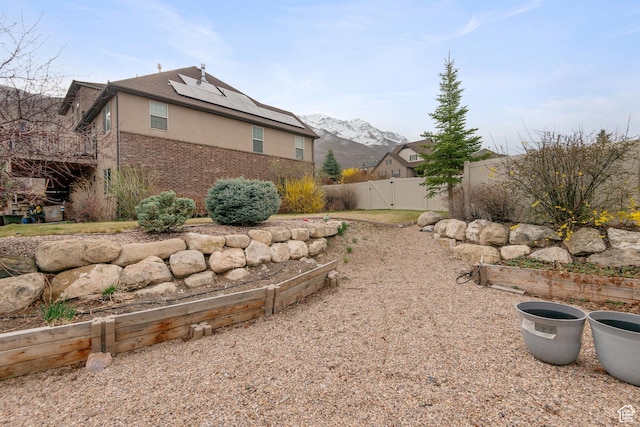 1035 E 300 S, Santaquin, UT 84655 - view of side of home featuring stucco siding, fence, a gate, a mountain view, and roof mounted solar panels