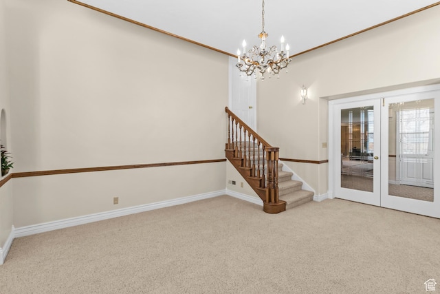 carpeted spare room with stairway, a notable chandelier, french doors, and baseboards