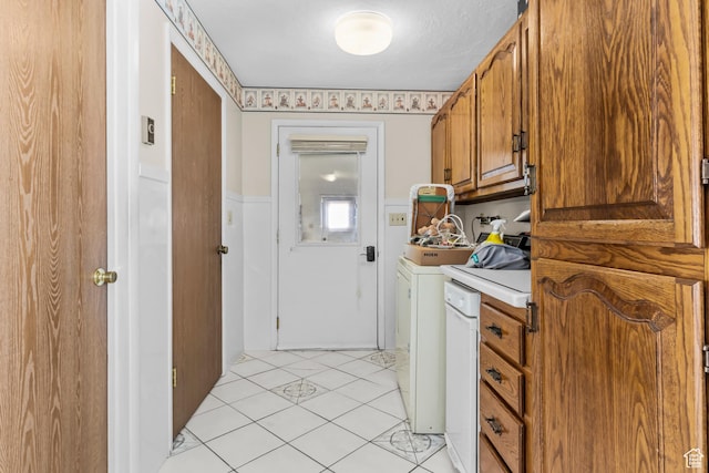 kitchen featuring light countertops, light tile patterned floors, brown cabinetry, and washer / dryer