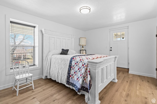 bedroom featuring light wood-type flooring, multiple windows, and baseboards