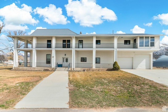 view of front facade with a balcony, covered porch, concrete driveway, a garage, and metal roof