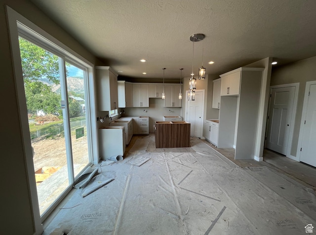 552 41st St, South Ogden, UT 84403 - kitchen featuring a textured ceiling, a kitchen island, white cabinets, decorative light fixtures, and recessed lighting